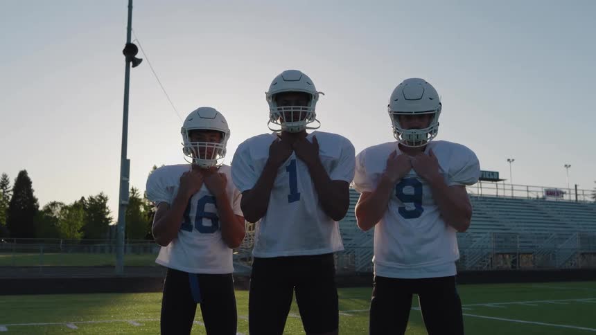 The football players stand together holding their jerseys