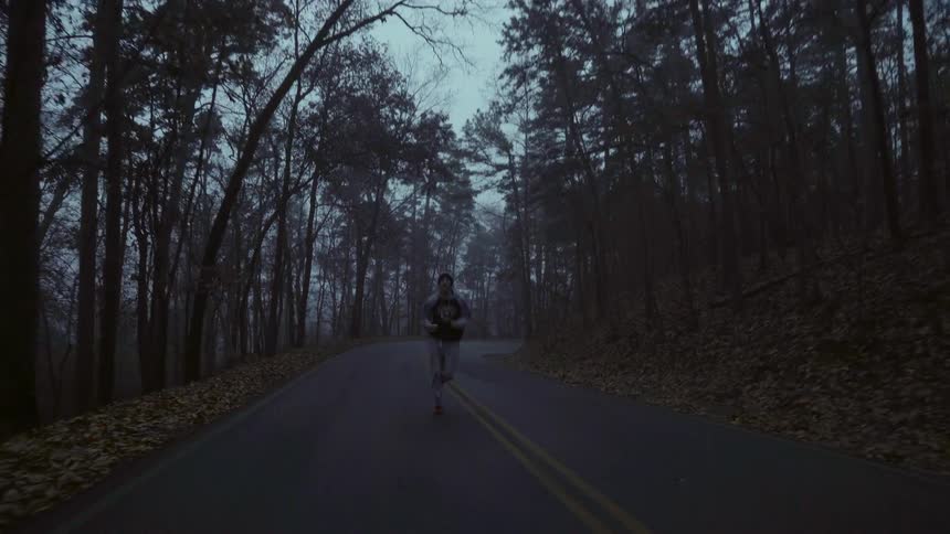 Man jogging on a tree lined road at sunrise