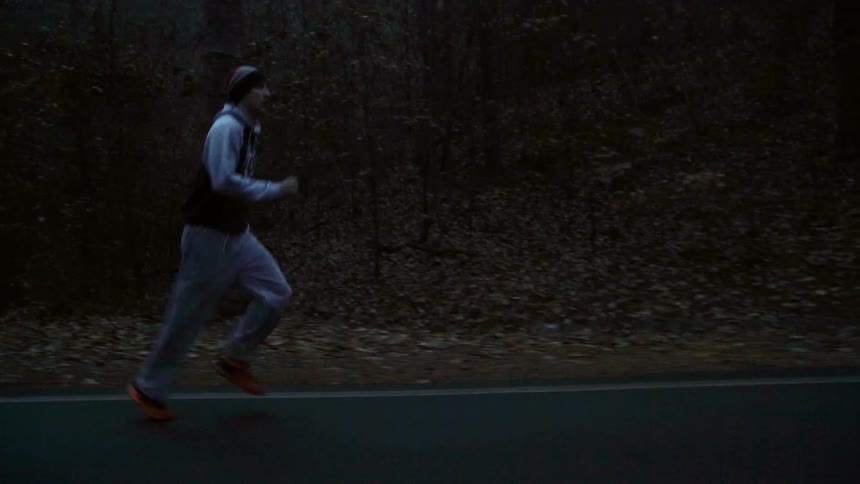 Man running down a country road next to woods