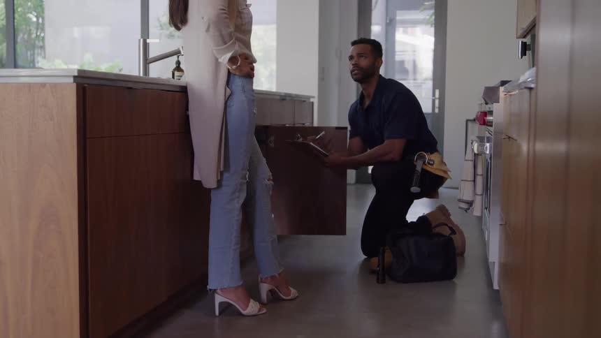 The plumber is talking with a customer in the kitchen