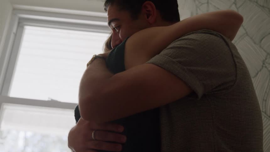 The couple having received the positive pregnancy test result exchanges joyful expressions and embraces in a tight hugthey pull back to smile at each other still holding the test before hugging again showing their excitement over the news