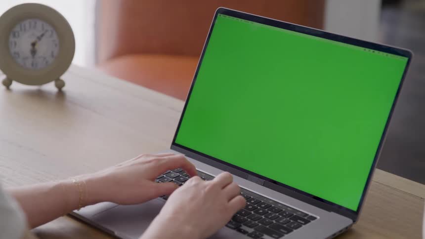 The woman is typing on a laptop at her desk