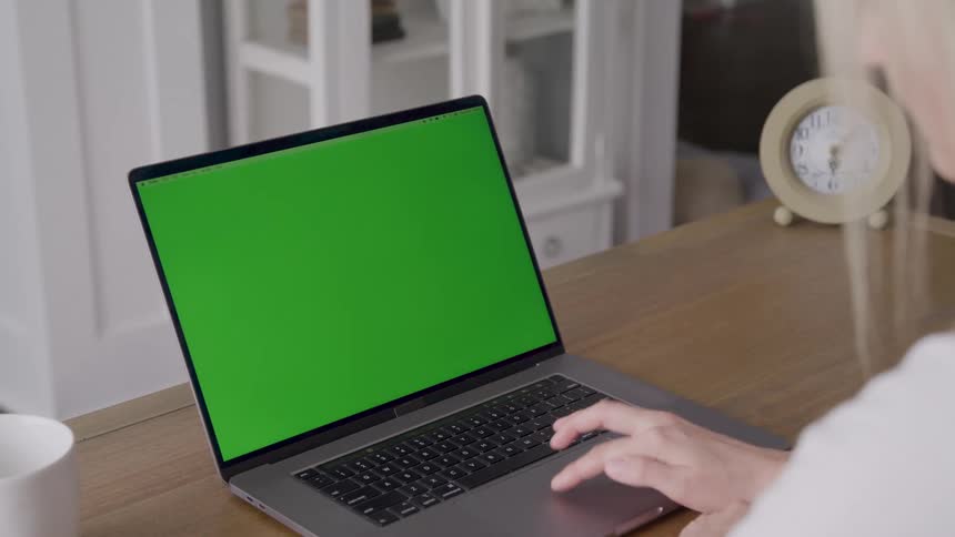 A woman uses her finger to swipe the touch pad of a laptop