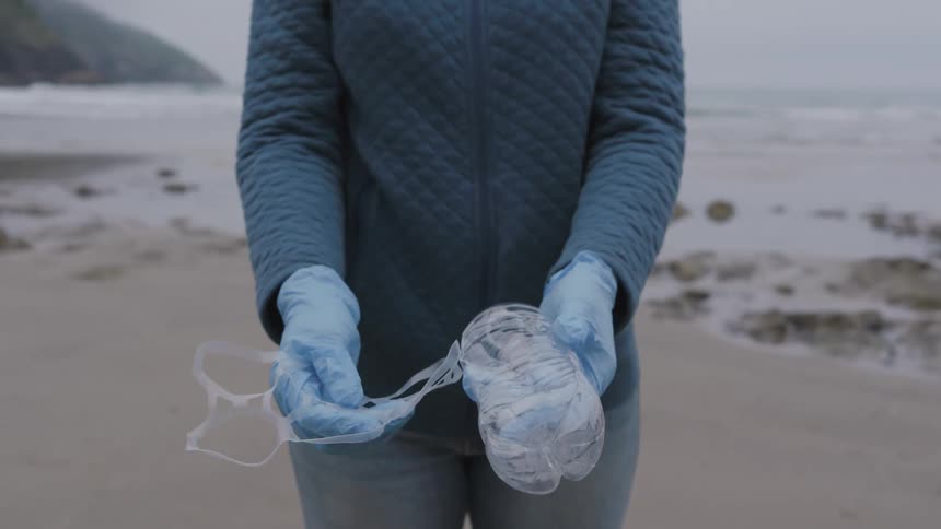 Person collects plastic waste on beach during environmental cleanup activity