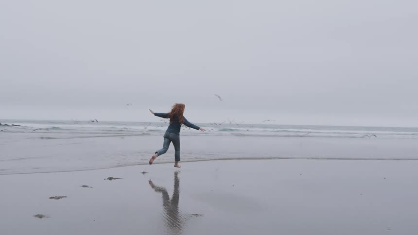 A young woman running across the wet sand at the outdoor beach during daytime