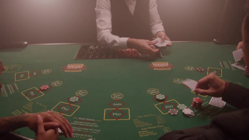 A male dealer dealing cards to players at a poker table in a casino