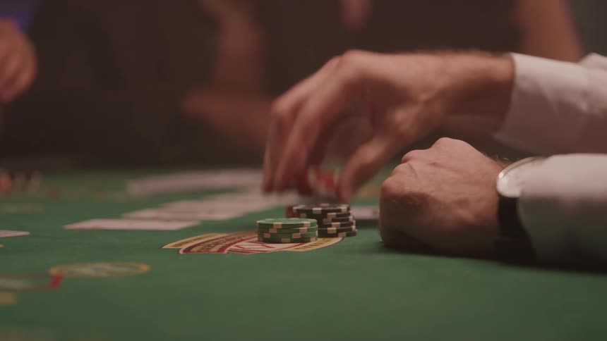 Close up of a male player handling poker chips while playing at a poker table