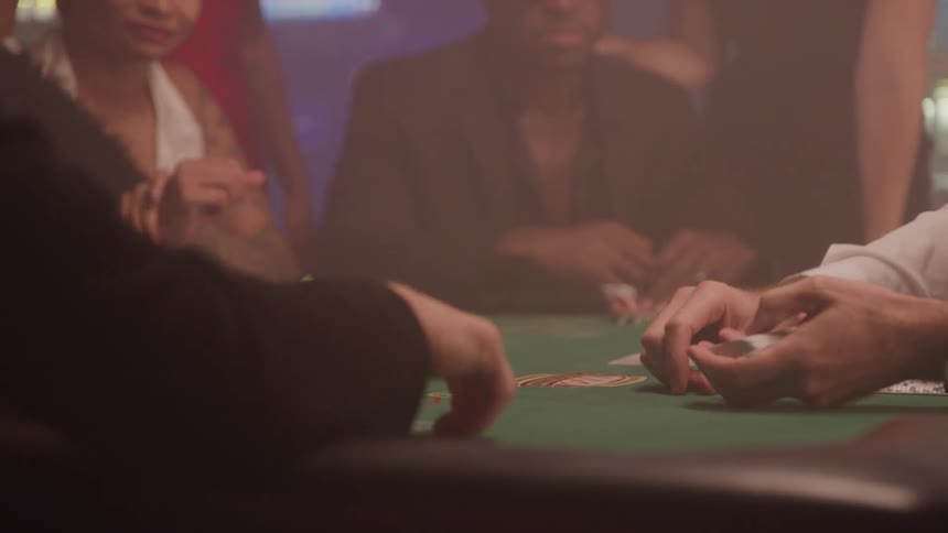 Card dealer putting cards over a table surrounded by players in a casino indoors