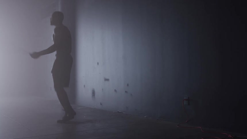 A young black man skipping during a fitness session indoors in a dark room