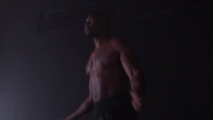 Muscular person in motion with bare torso in dark indoor setting and foggy atmosphere