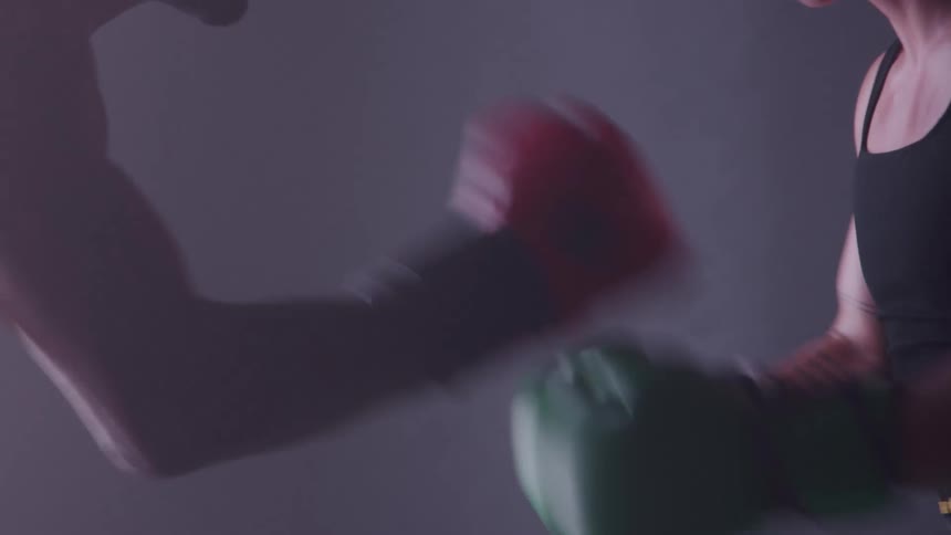 Two men wearing boxing gloves stand facetoface clapping their gloves together in anticipation of a fight