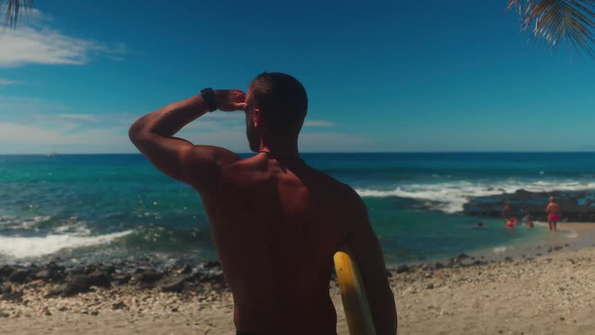 Man holding a surfboard looking at the ocean