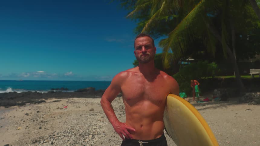 Portrait of a young man carrying a surf board while standing at the beach in daytime