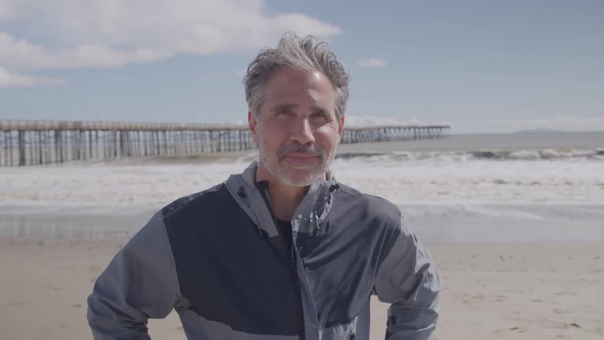 The man is smiling on the coast