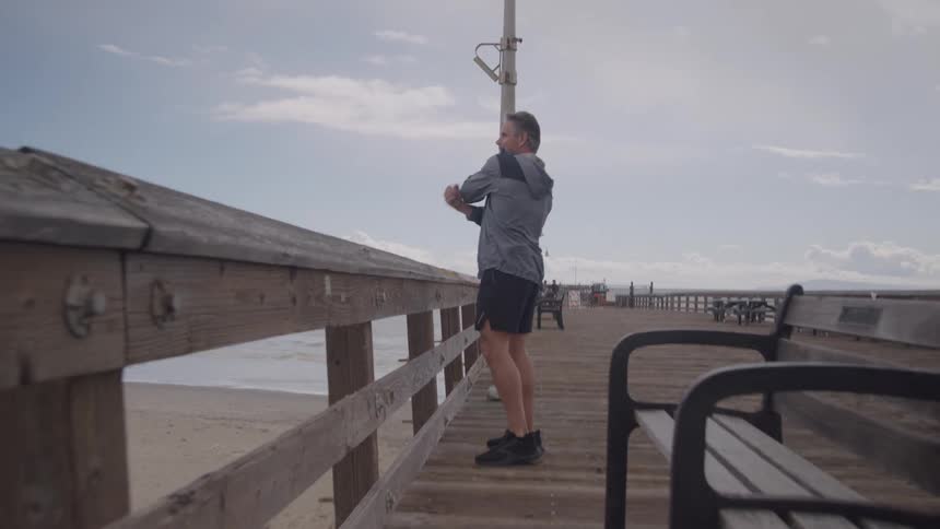 Man stretching his arms on a seaside pier