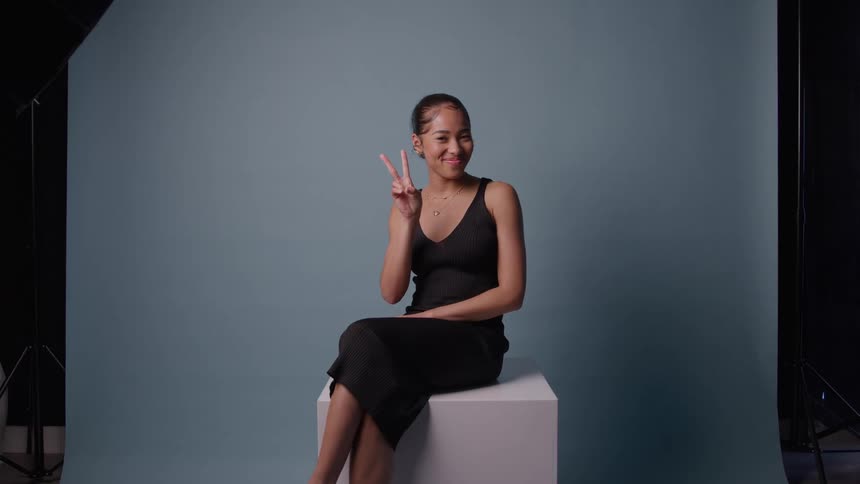 Portrait of a young black woman making a happy pose while sitting in a photography studio