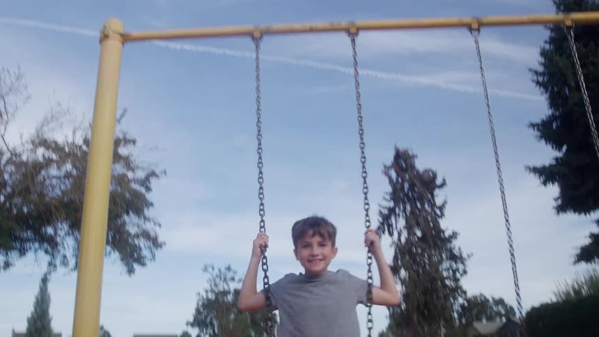 Boy rides a swing in a neighborhood park