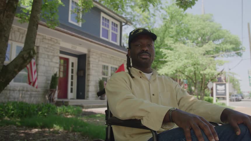 Man sitting in a wheelchair in front of a house