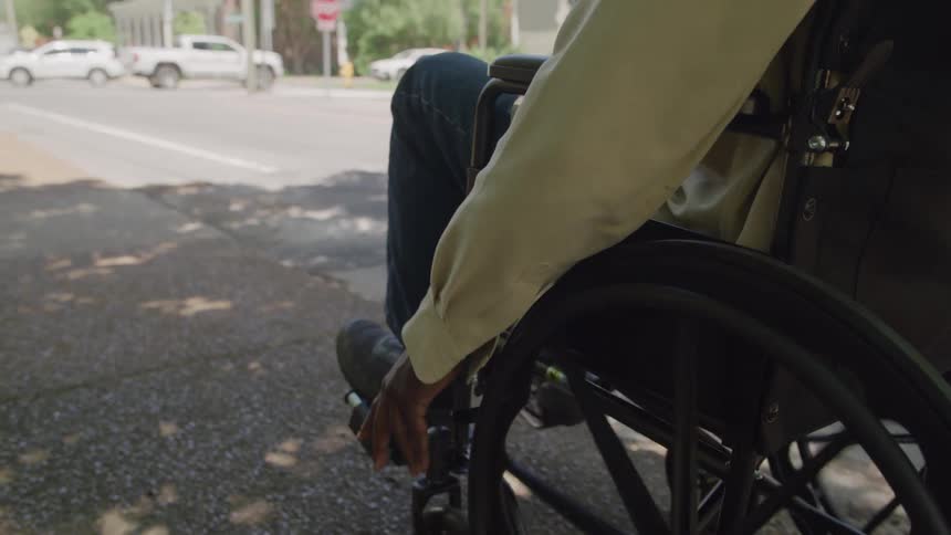 The person moves in their wheelchair up the road