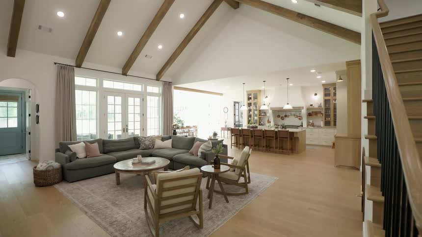 Modern openconcept space with large sofa kitchen island and wood staircase under beamed ceiling