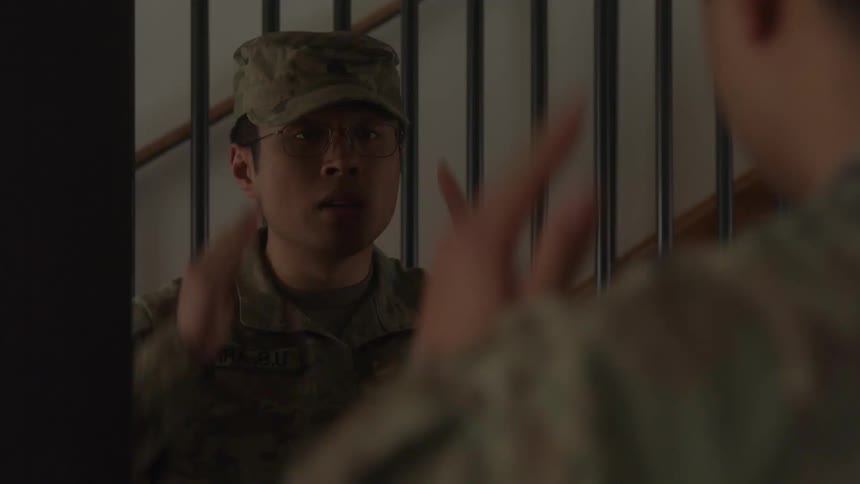 Soldier in camouflage uniform putting on his beret in front of a mirror