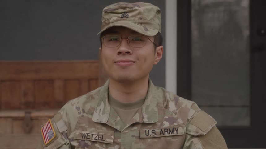A portrait of a man standing outdoors in a military outfit