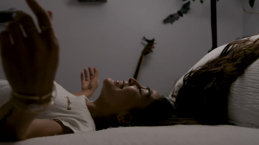 The woman falls into her bed smiling
