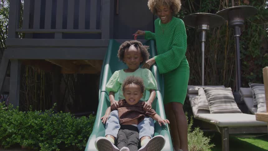 The mother watches her daughters go down the slide