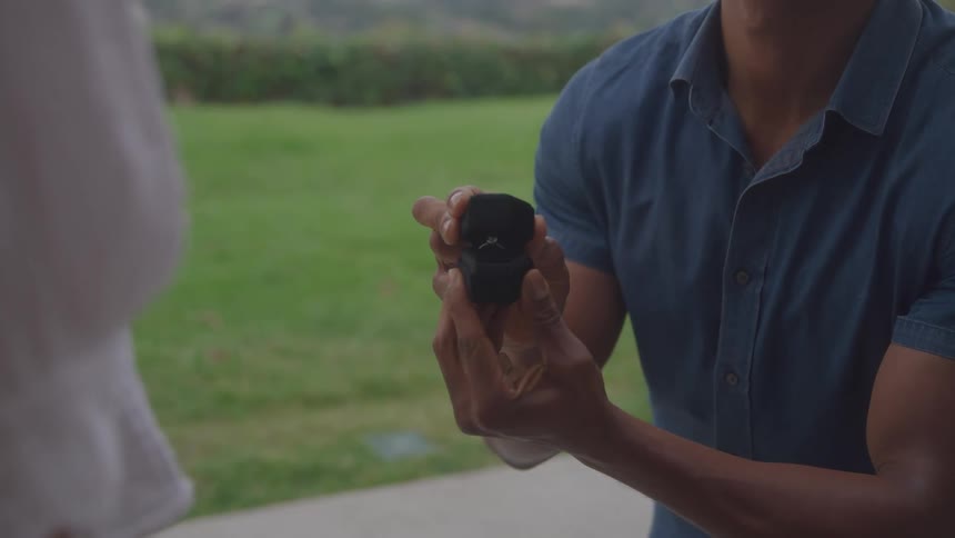 A man is proposing to his girlfriend while holding the engagement ring