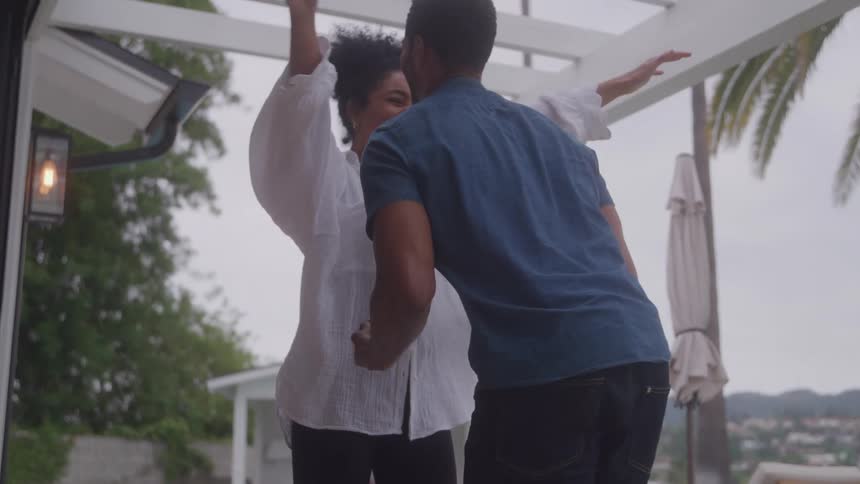 Man kneels holding an open ring box in front of another person as part of a marriage proposal and they embrace