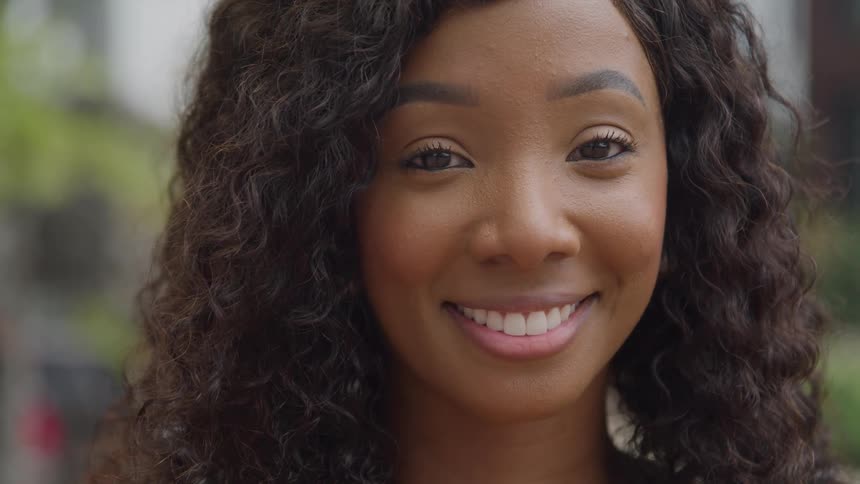 A young woman with long curly hair is smiling