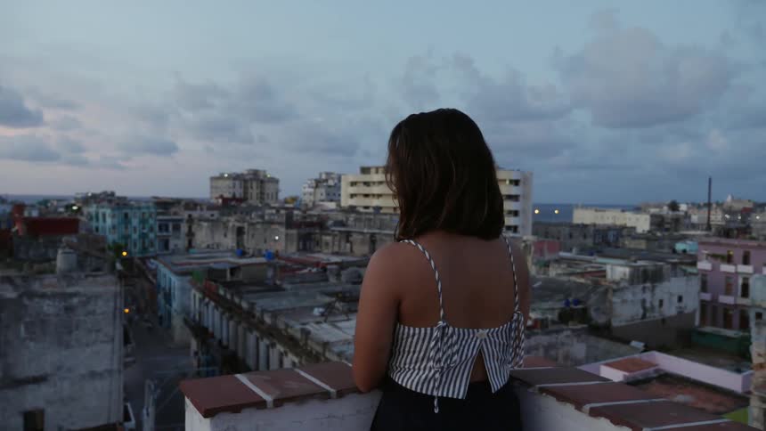 A woman looks out over a town from a roof