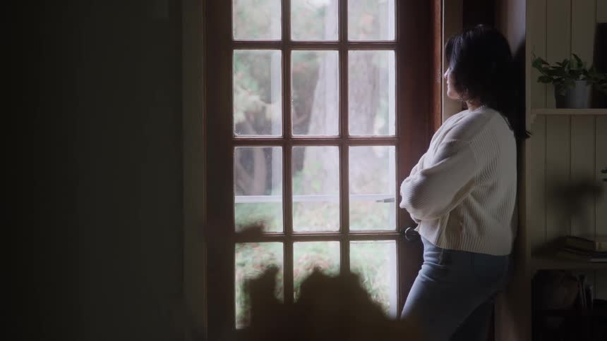 Woman standing in front of a glass door looking outside