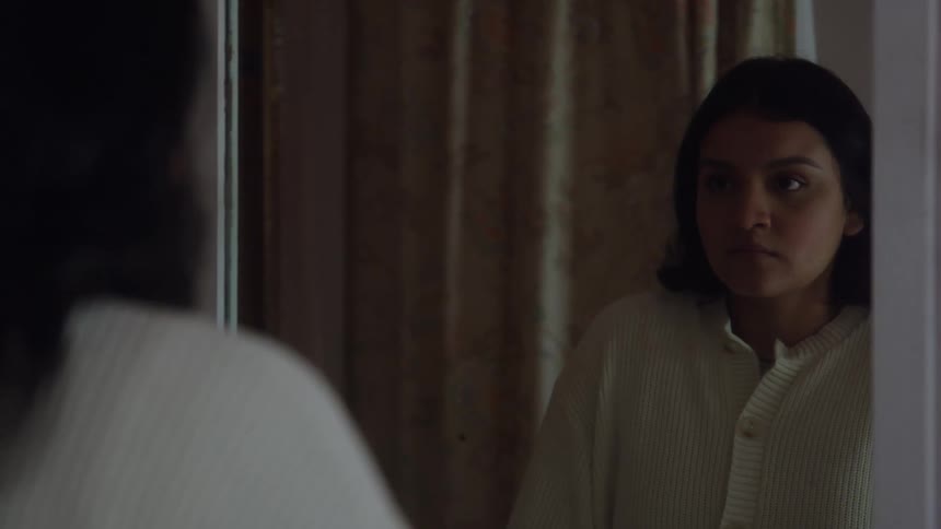 Woman looks at her reflection in the mirror indoors