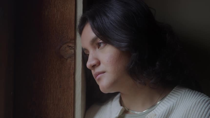 Woman leaning against the window frame looking outside