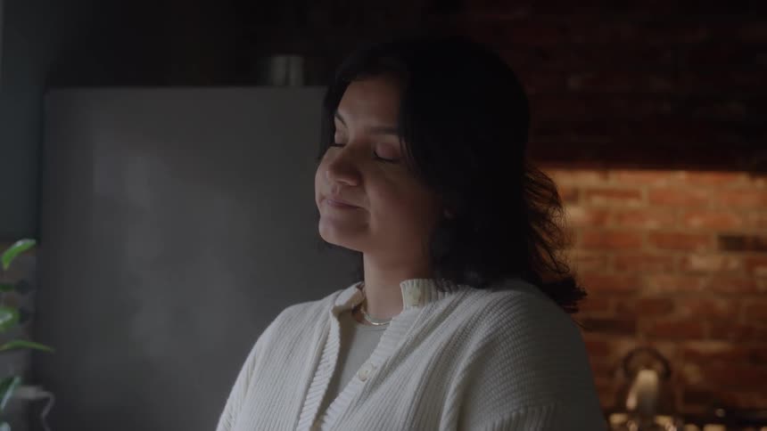 A young woman stands by the sink in her kitchen her posture heavy with sadness the quiet room reflects her mood as she gazes downward lost in thought