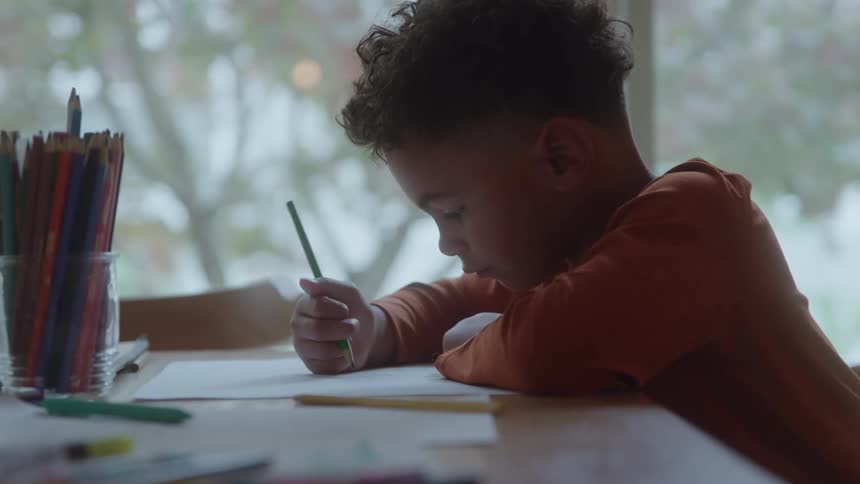 Boy leaning on the table drawing with a pencil