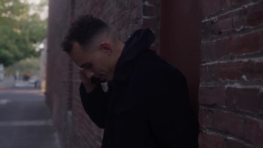 Man leaning against a brick wall talking on the phone