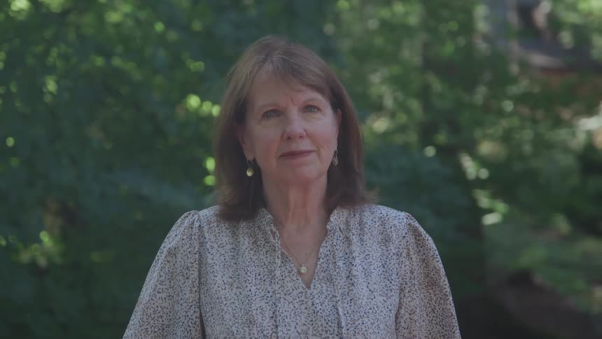 Woman in a patterned blouse in a treefilled outdoor area