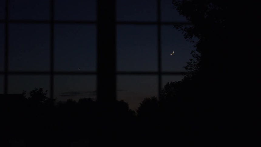 View from windows inside a house of a crescent moon in the night sky
