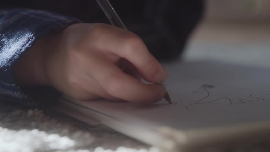 Young person lying on a rug draws with a pen