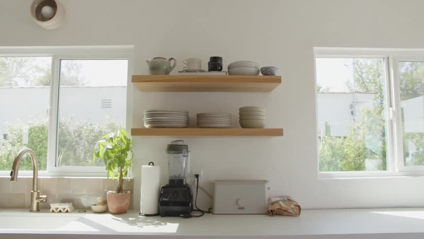 A kitchen with a shelf containing some utensils and a white countertop with some appliances