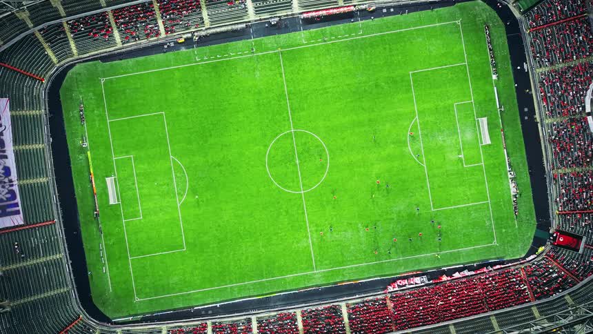 Soccer field seen from above with players spread out and filled stands