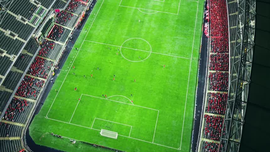 Soccer match seen from above with players spread across the field and crowded stands