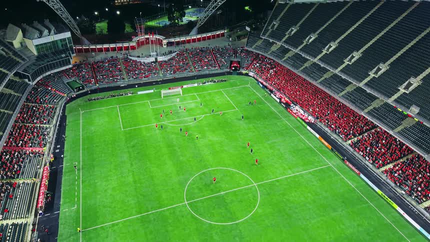 Soccer fans fill the stands during a soccer game at night