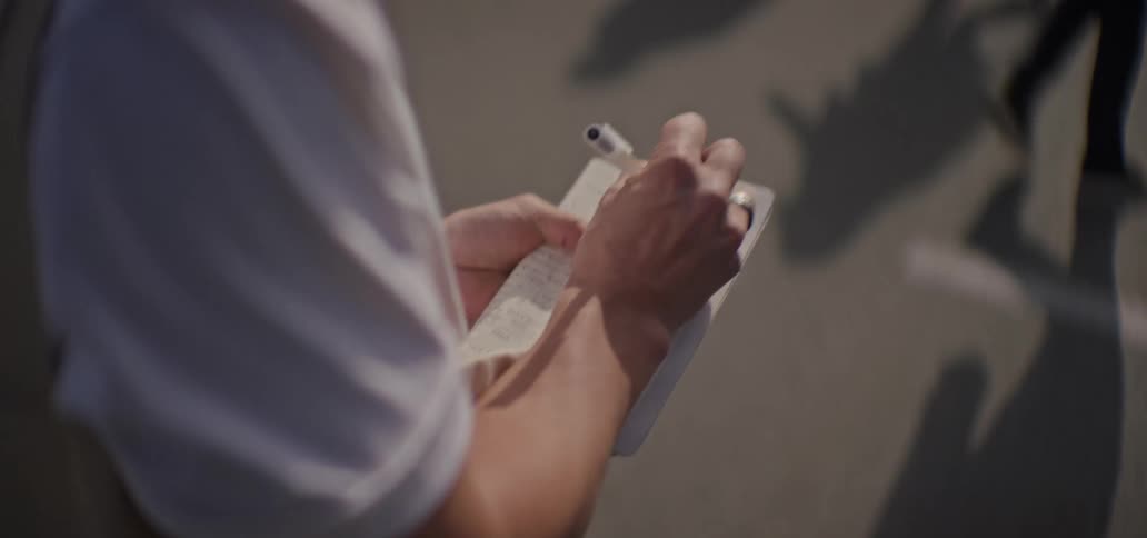 The man is writing in his notebook as he walks