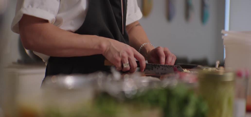 Cook slices ingredients on a cutting board using a large knife