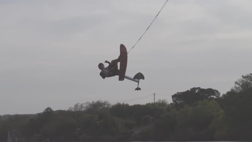 Man flips over on a wakeboard above water and splashes back down