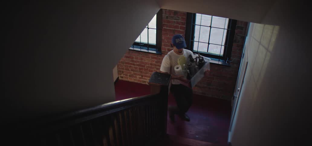 Man walks up a staircase carrying a transparent plastic box with items