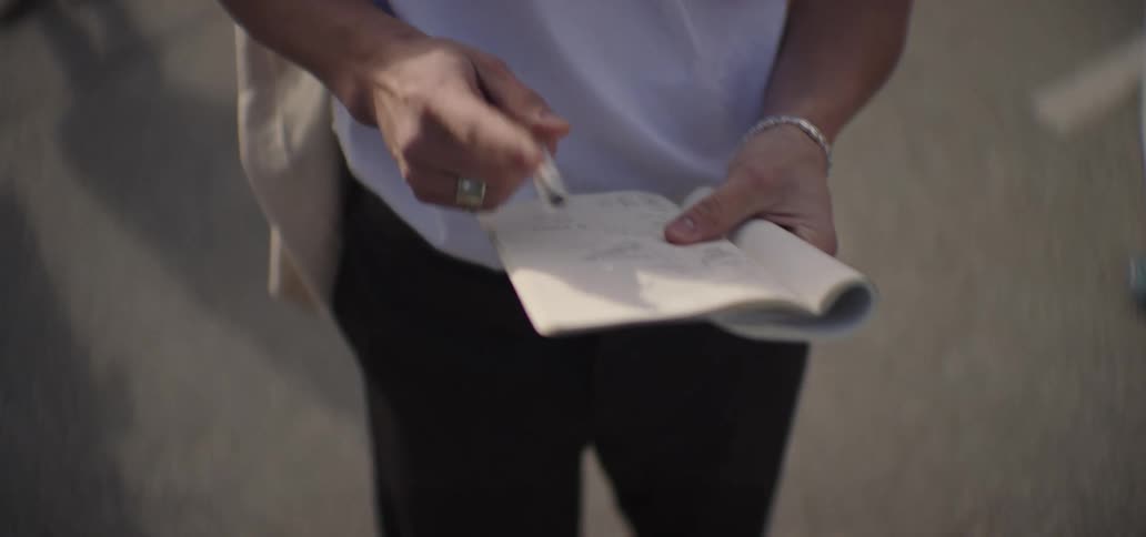 Man walking through an outdoor marketplace writing in his notebook